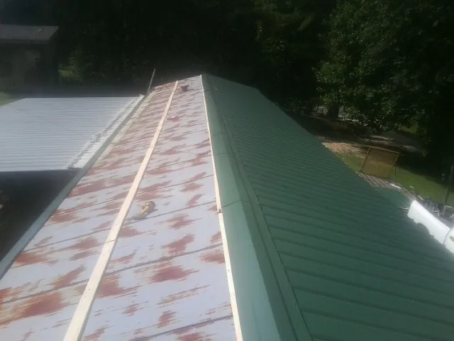 Old rusted panels beside newly installed green metal roofing — Wind Damage Roof Repair by Roofing Brothers in Harrisburg