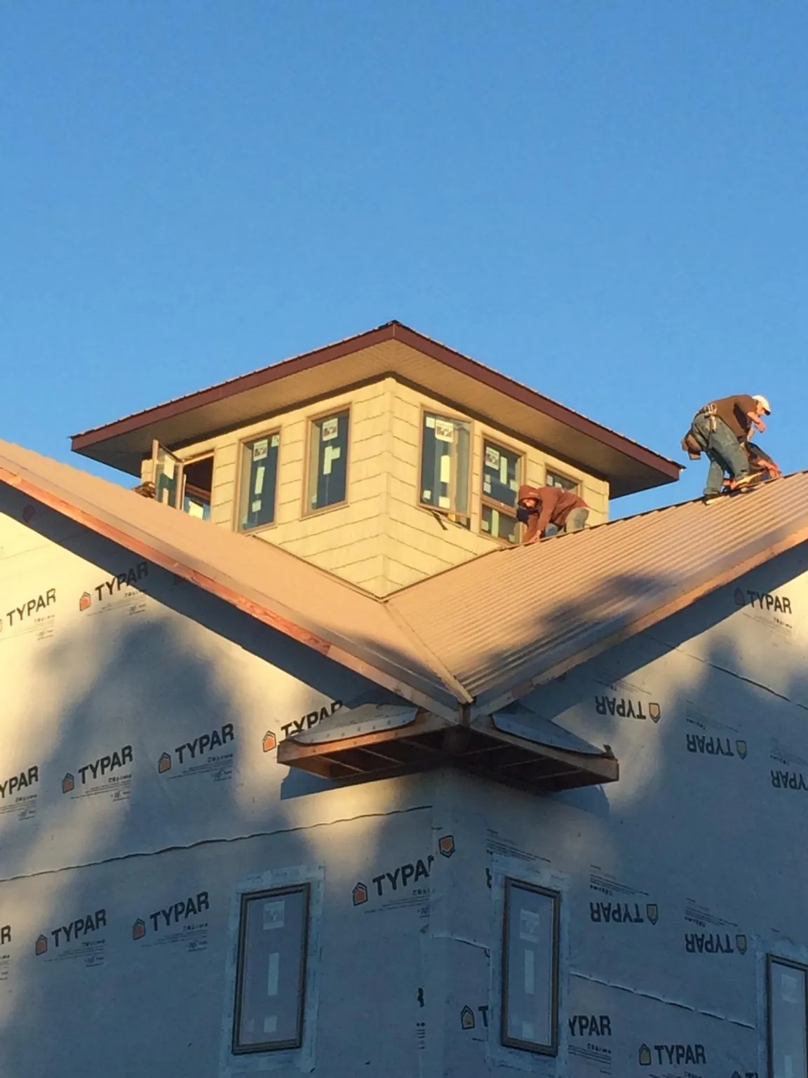 Roofers working around a rooftop cupola on a new metal roof at sunset — Roof Waterproofing in Harrisburg by Roofing Brothers